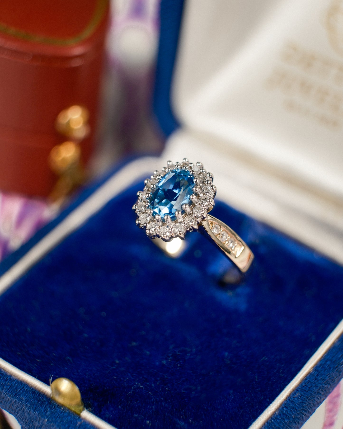 Een vintage ring in een fluwelen sieradendoosje met een blauwe topaas en diamanten van 9k geelgoud, product foto van de lijn Milena van The Vintage Company