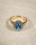 Een vintage ring liggend op steen met een blauwe topaas en diamanten van 9k geelgoud, product foto van de lijn Milena van The Vintage Company